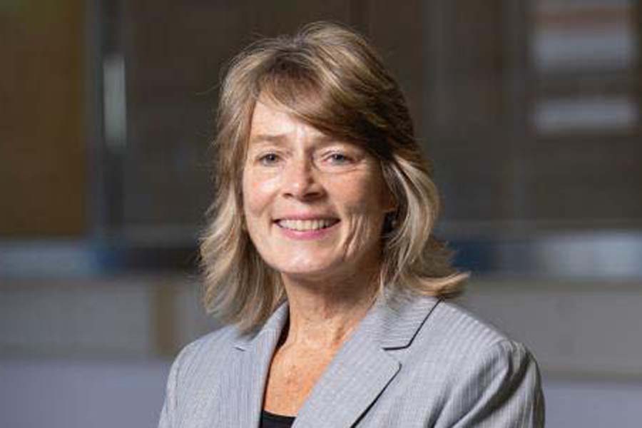 Woman standing in front of an out of focus and dark background.