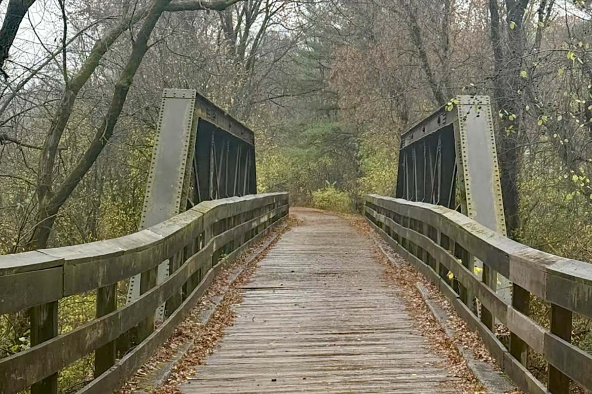 A wooden deck bridge held up by heavy metal railroad construction.