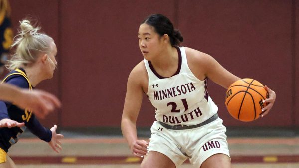 A woman dribbles the basketball in an attempt to get around her opponent.