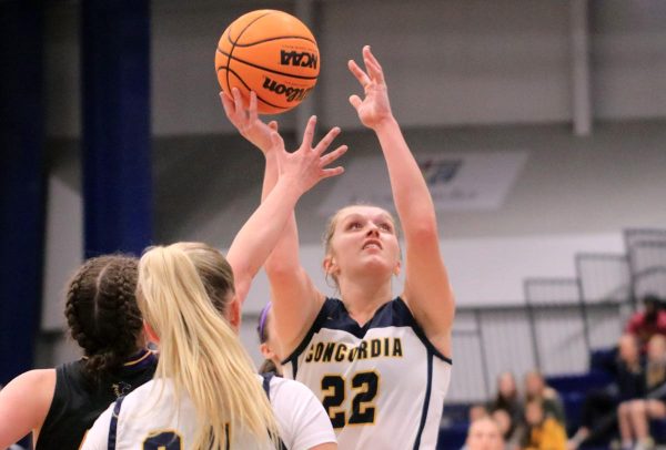 A woman basketball player takes a shot.