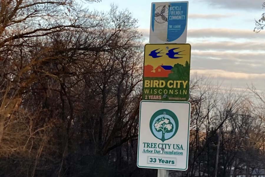 Three signs with shrubs and sky in the background