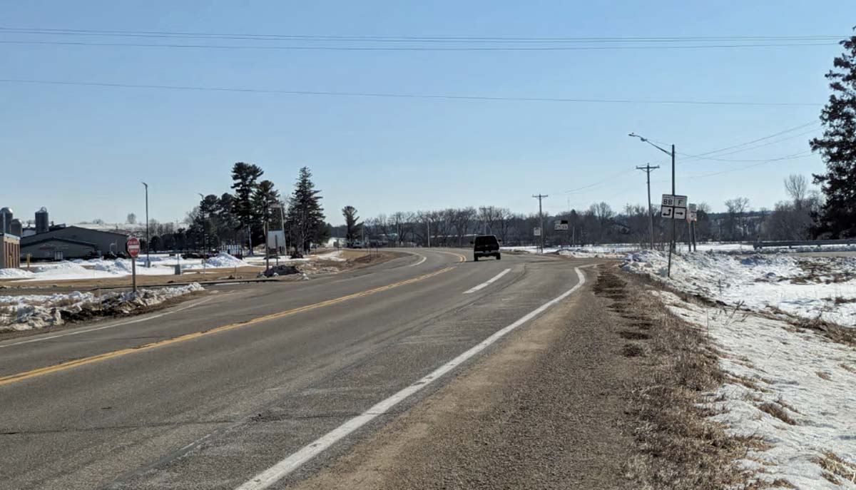 A car in the distance drives down a rural road.