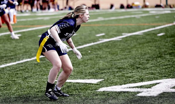 A women's flag football player awaits the snap of the football.