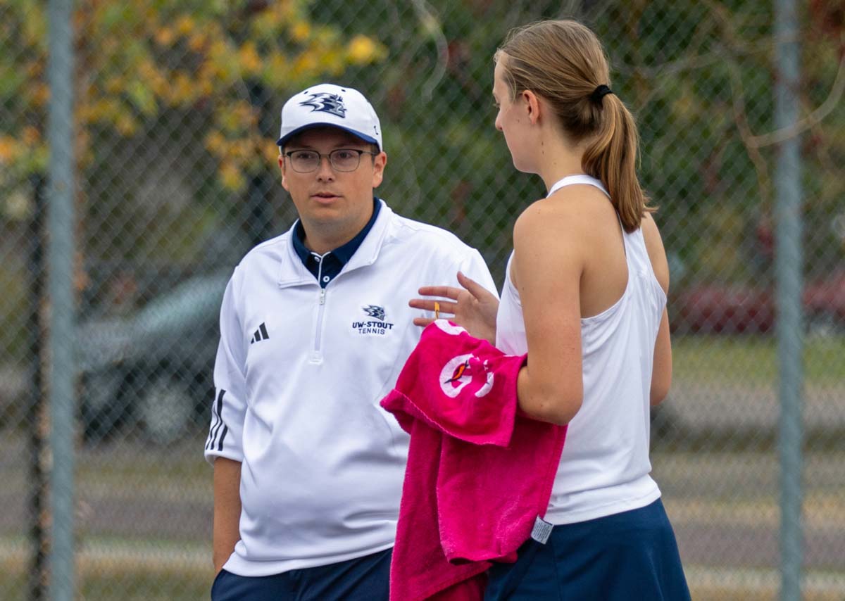 A tennis coach talks with a member of his team between sets.