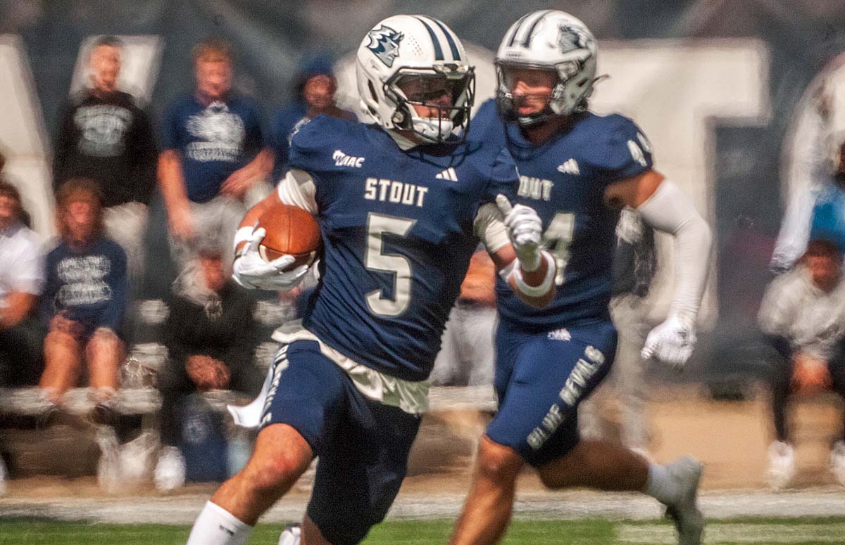 A football player runs up the field while returning an interception.
