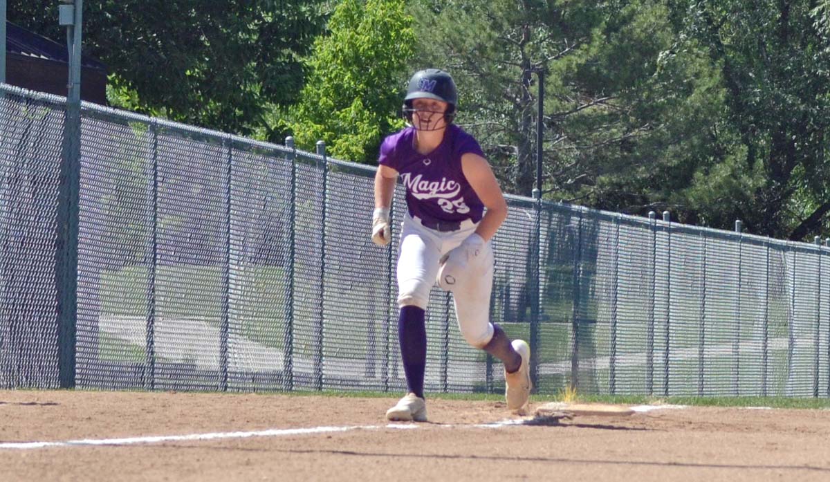 A softball player rounds third base.