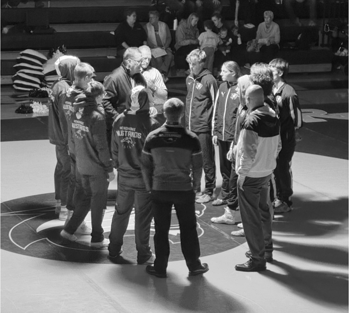 High school wrestling teams meet at the middle of the mat before the meet.