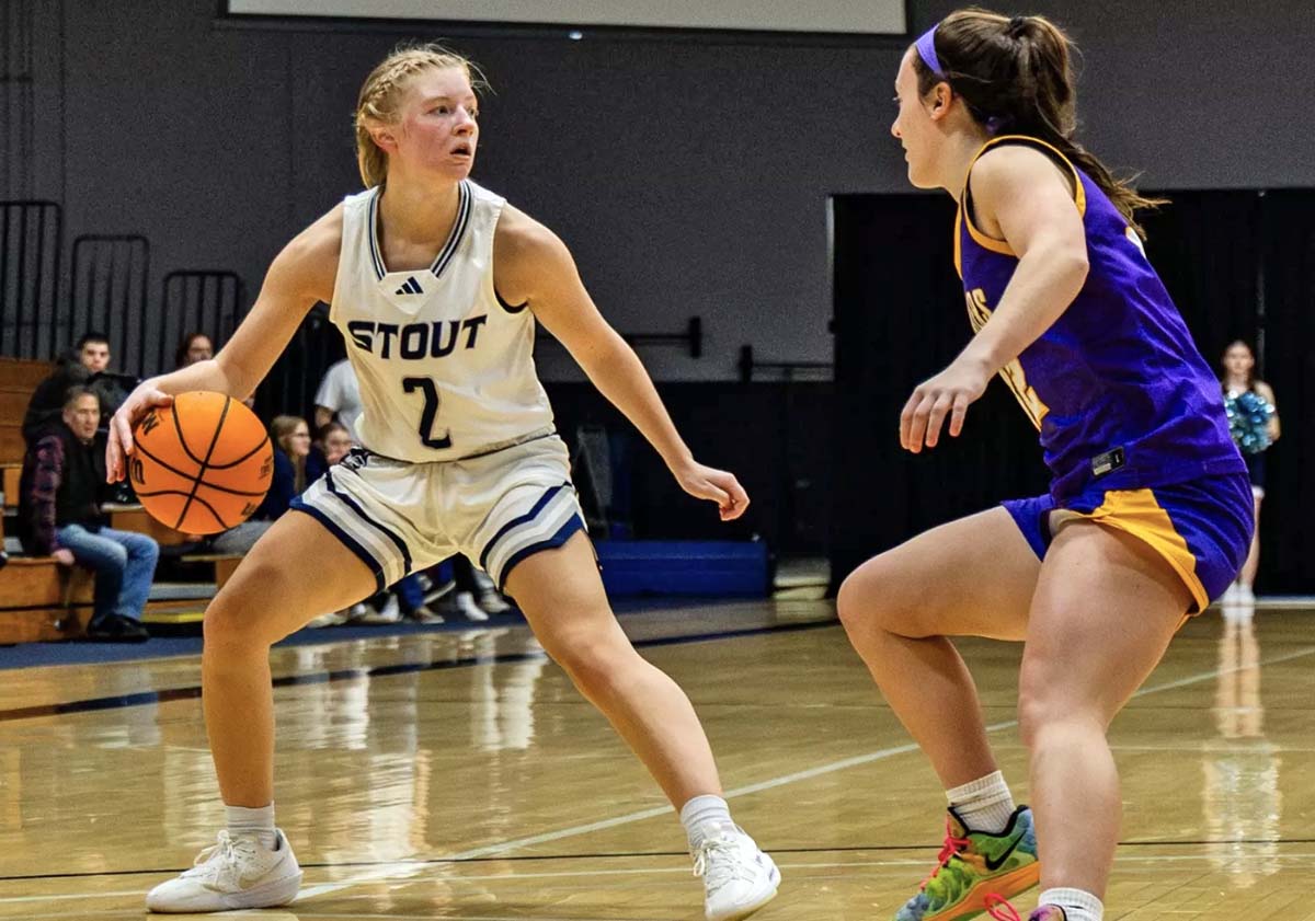 A women's basketball player in a white UW-Stout uniform holds off a UW-Stevens Point player in a purple and gold uniform in a game at Johnson Fieldhouse in January, 2026.
