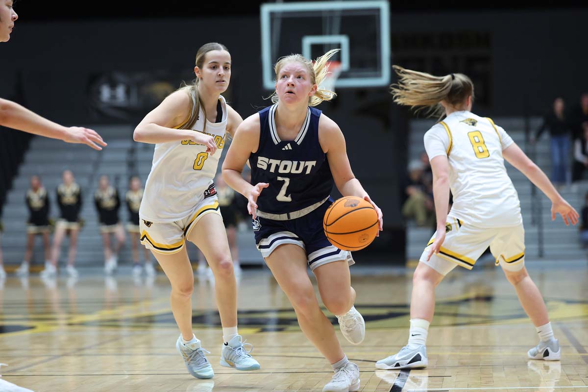 UW-Stout's Mary Berg, wearing a blue uniform, against UW-Oshkosh, wearing white uniforms, in a game at Kolf Center in Oshkosh on February 14, 2026.