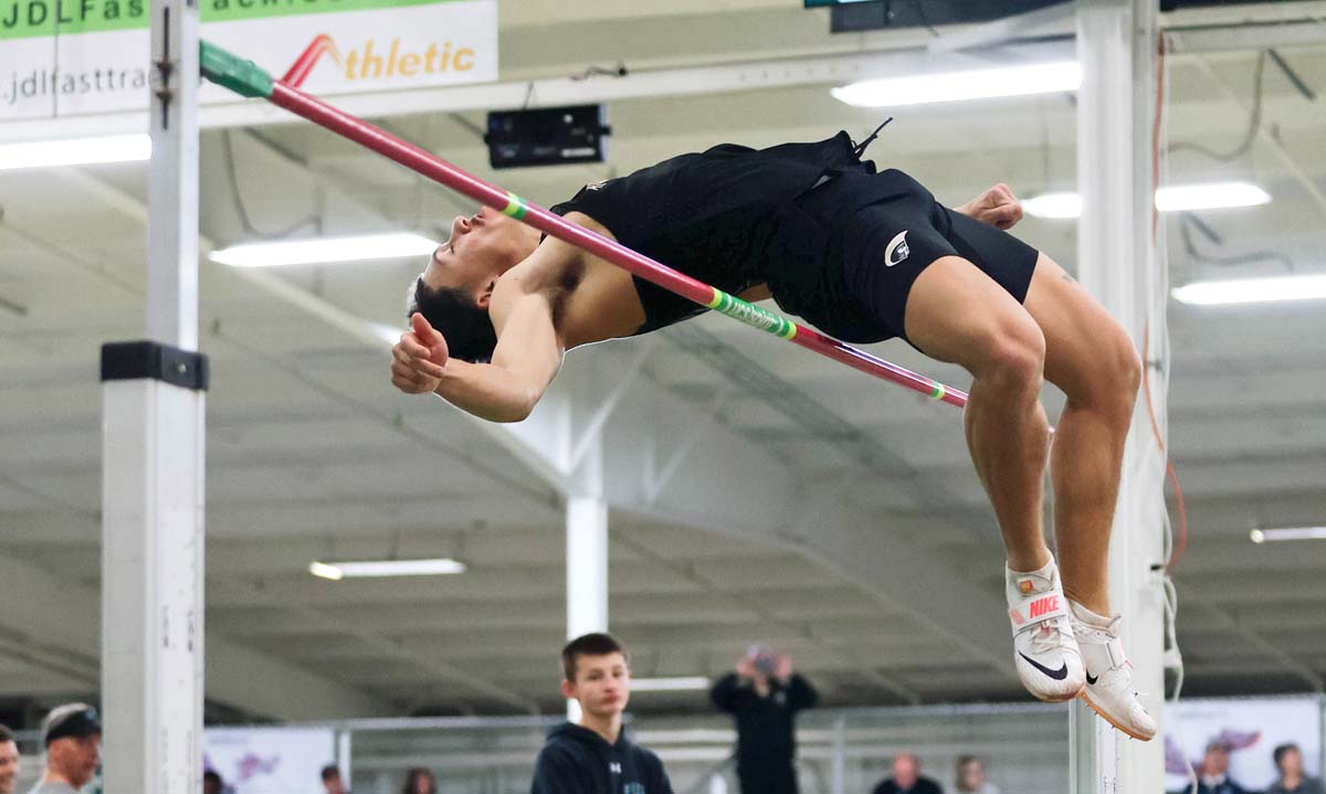 a student-athletes leaps over the high jump bar.