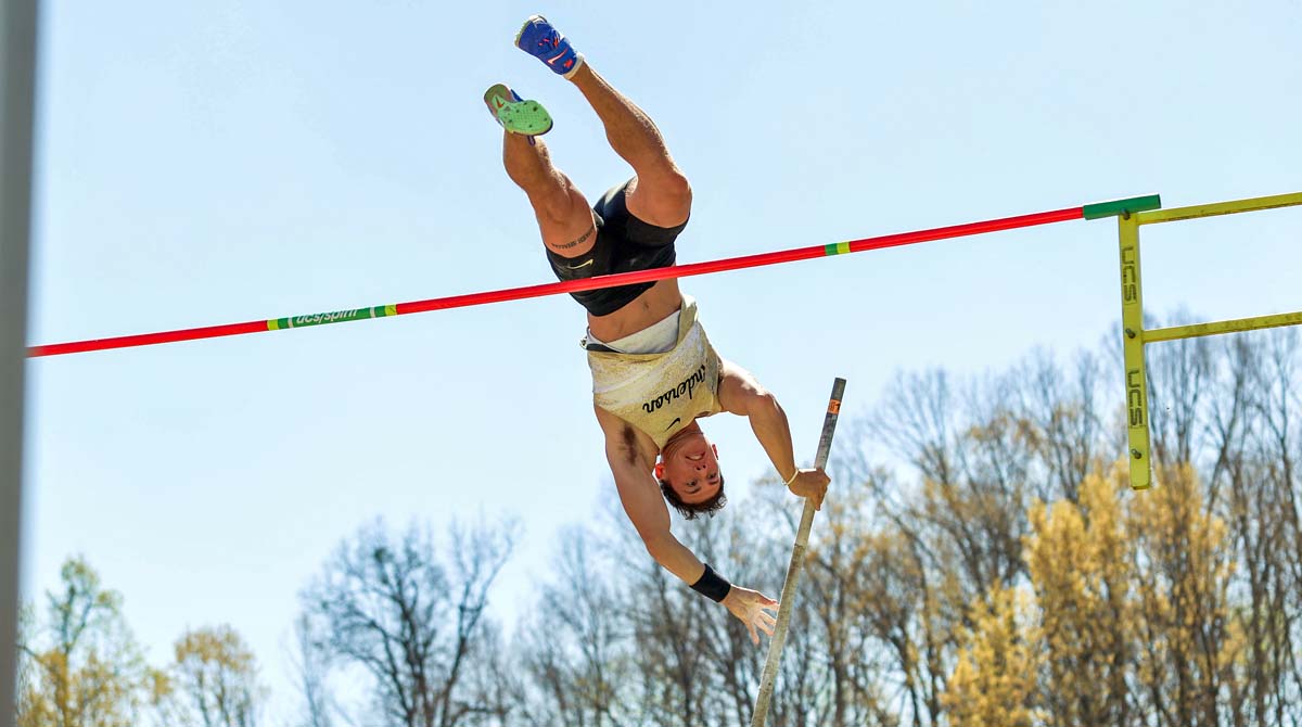 A student-athlete clears the pole vault bar.