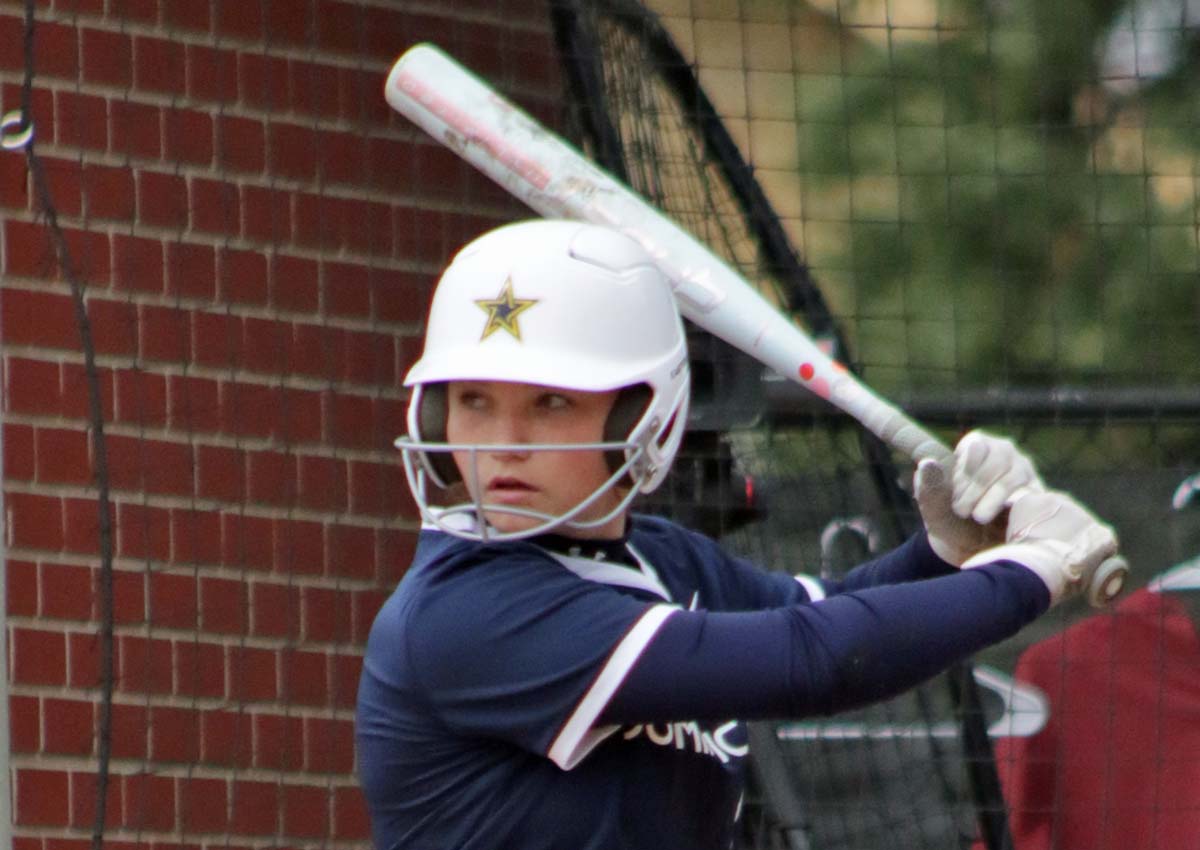 A Dominican University batter in a navy blue jersey keeps her eye on the softball.