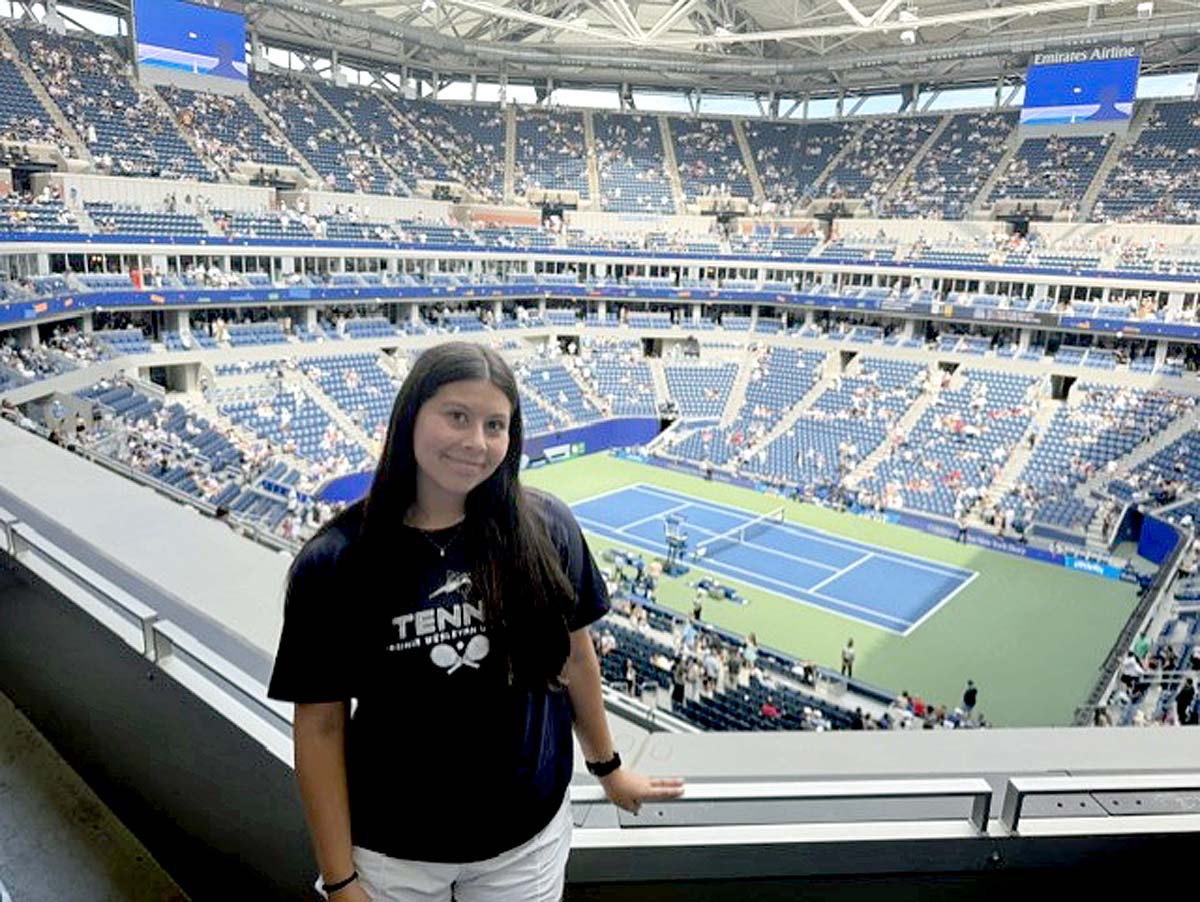 A woman in a dark blue t-shirt stands in the upper deck at the US Open.