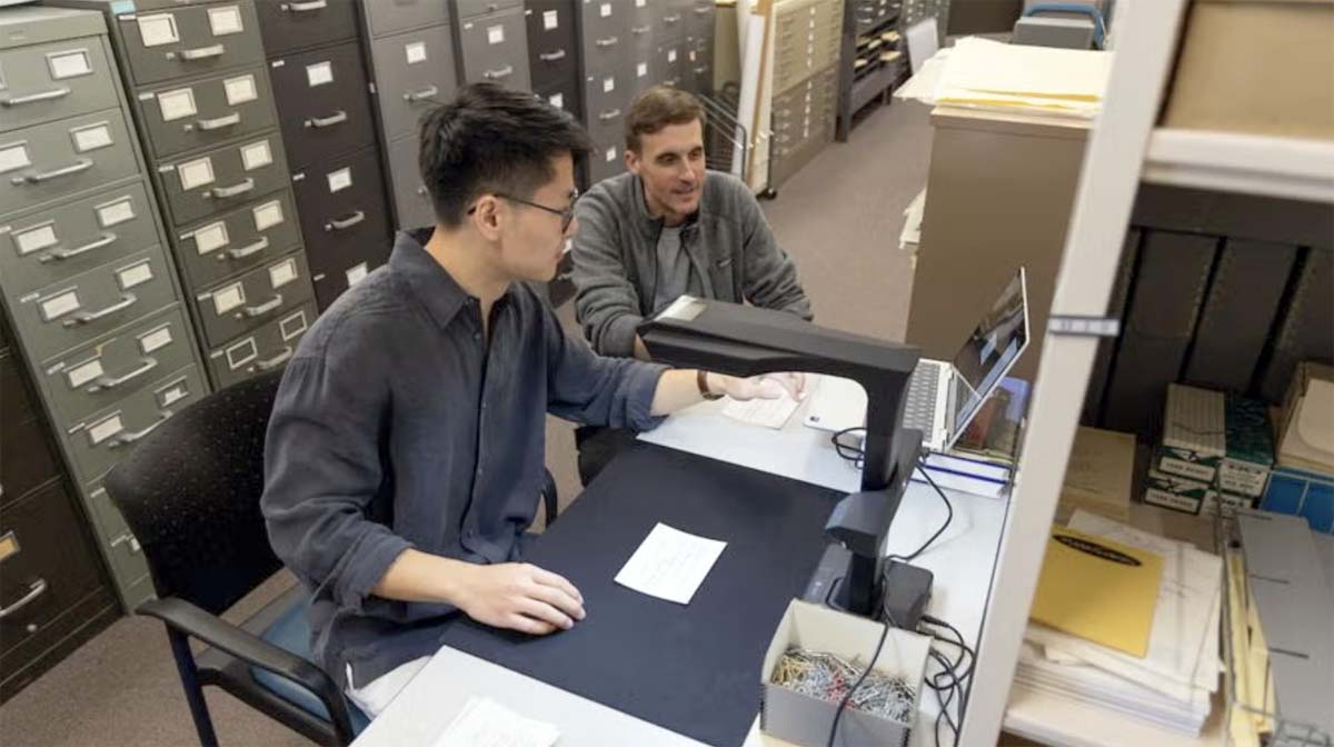 Two men in a library utilizing a digital scanner.